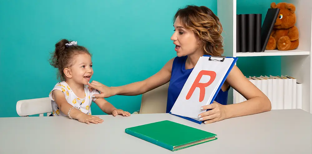Speech therapist teaching a child to pronounce sounds using letter cards during therapy