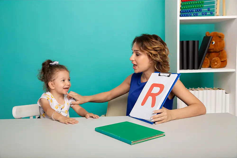 Speech therapist helping a child practice the letter R sound during speech therapy